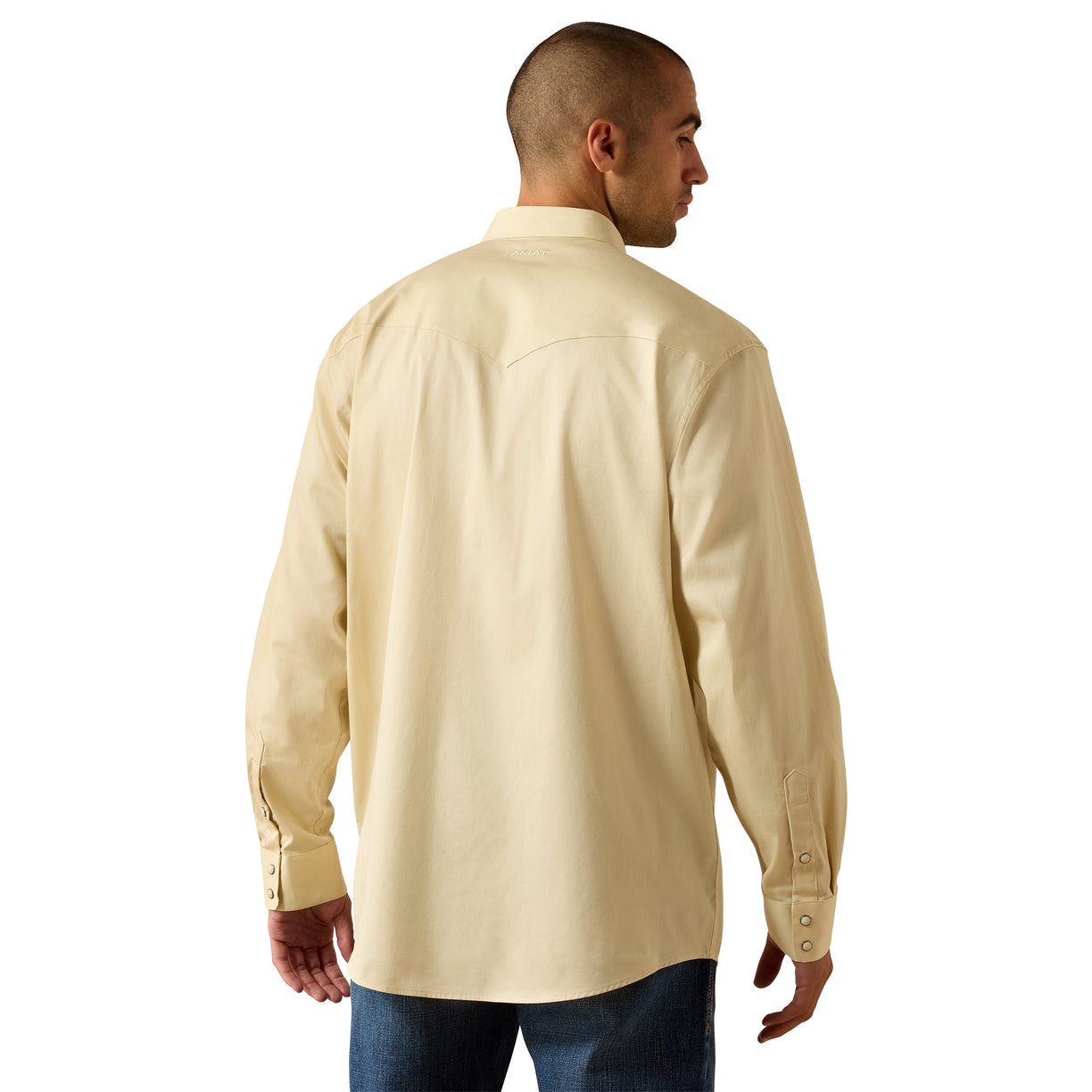 A man shown from the back wearing a light beige long-sleeve button-up shirt and blue jeans, photographed against a plain white background.
