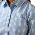 Close-up of a blue striped shirt with a brand logo on the chest pocket.