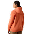 Person wearing an orange hoodie with a brand logo on the back, standing against a white background