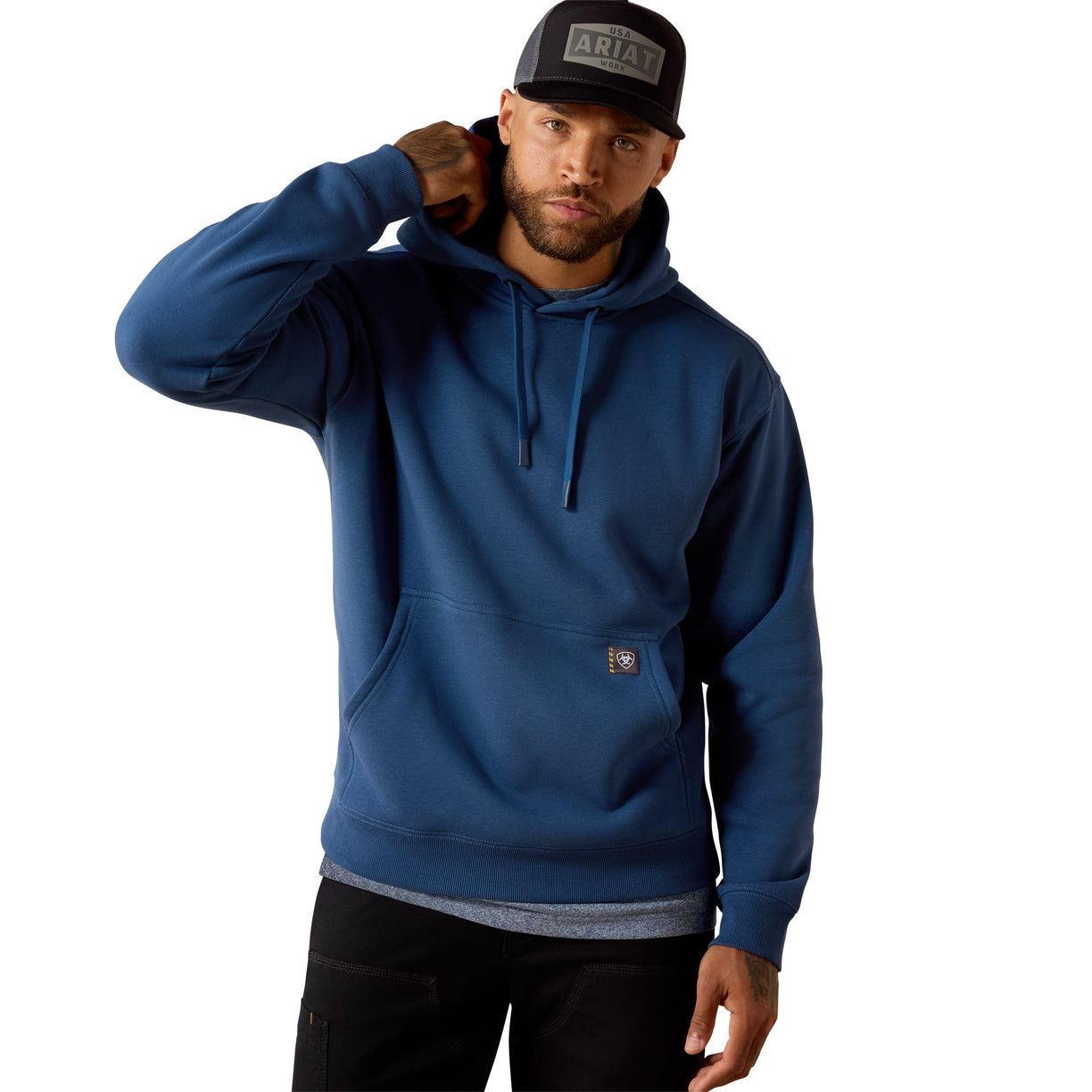 Man wearing a blue hoodie and black cap with 'Ariat' logo on a white background