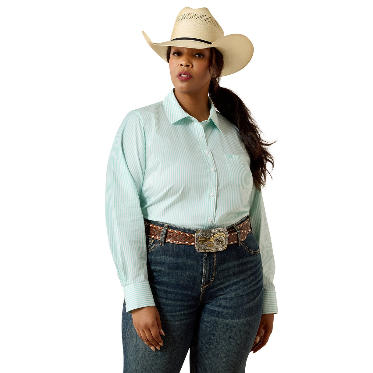 A woman modeling a light mint green and white vertically striped western long-sleeve shirt, paired with dark blue jeans, a brown western belt, and a beige cowboy hat, against a solid white background.