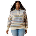 A woman modeling a striped pullover hoodie with a multicolor pattern of beige, blue, yellow, and brown horizontal stripes, paired with light blue jeans against a plain white background.
