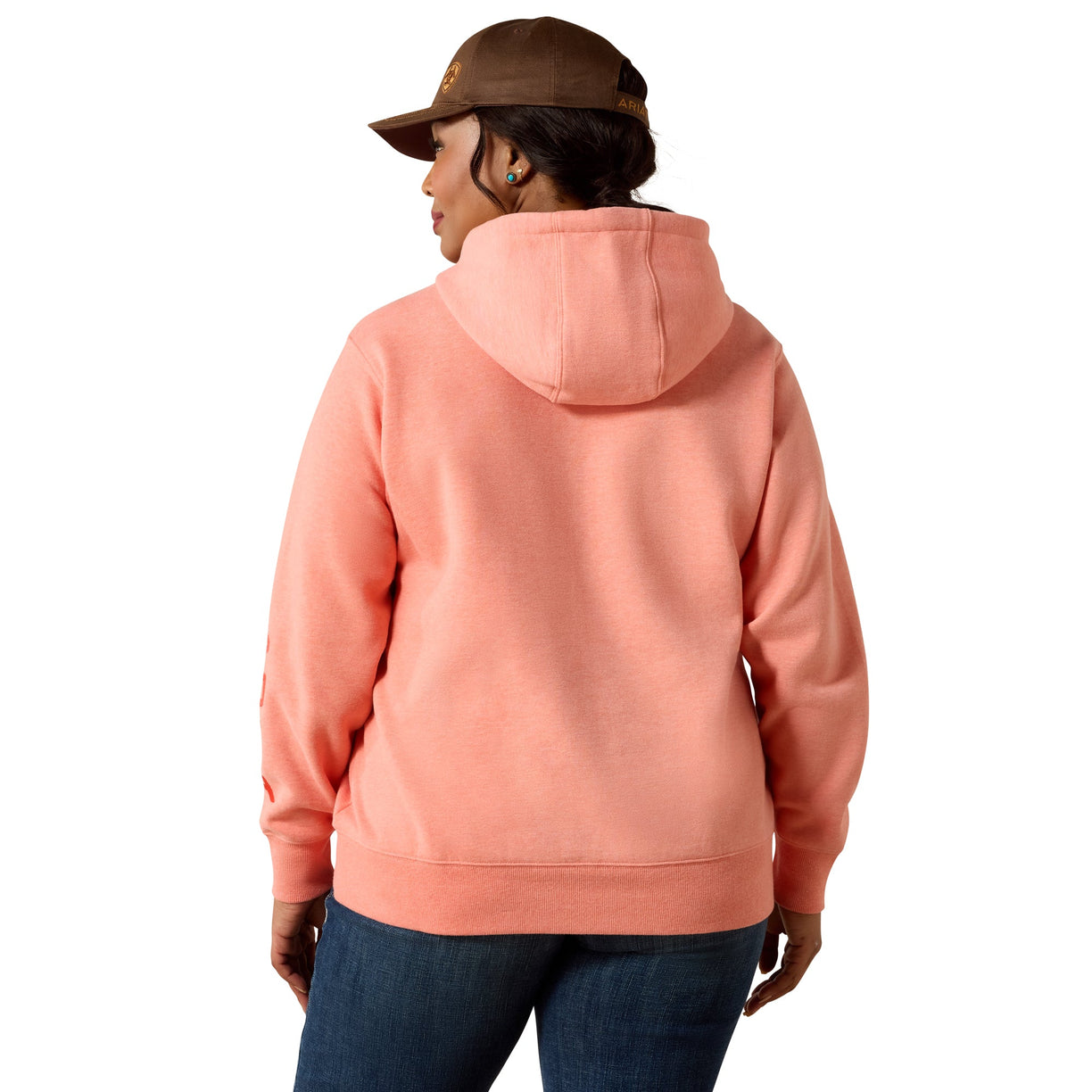 A woman shown from the back wearing a peach-colored pullover hoodie and a brown baseball cap, set against a plain white background.