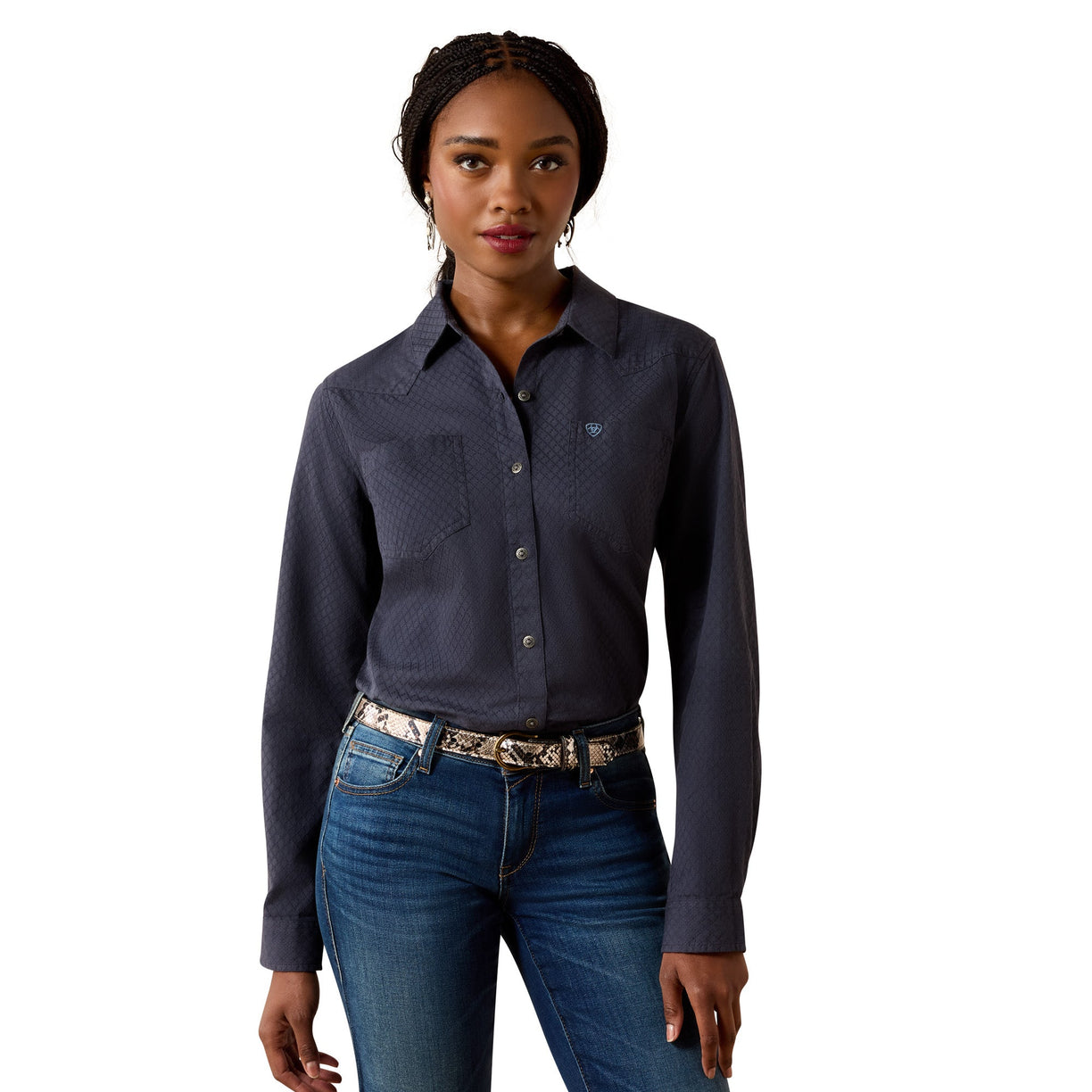 A woman modeling a dark slate blue long-sleeve western-style button-up shirt with a textured pattern, paired with blue jeans and a patterned belt, against a solid white background.