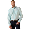 Man wearing a light blue button-up shirt and dark jeans on a white background