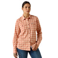 Woman wearing a coral plaid long sleeve work shirt with chest pockets