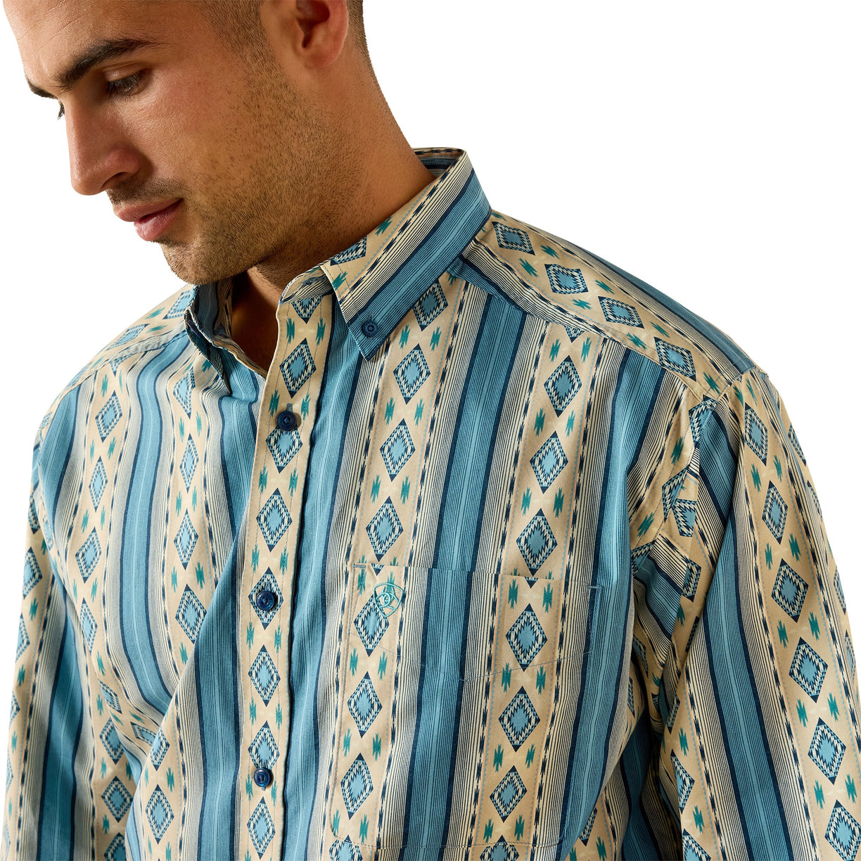 A man wearing a long-sleeve button-down shirt with vertical stripes and diamond geometric patterns in shades of blue, teal, and beige.