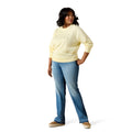 Woman wearing a light yellow sweater and blue jeans on a white background