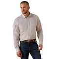A man wearing a light beige and white micro-patterned button-down shirt with a small blue embroidered logo on the chest, paired with dark blue jeans and a brown belt, against a solid white background.