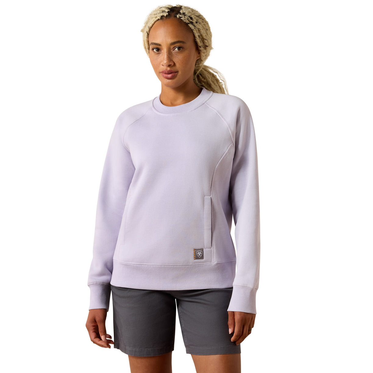 Woman wearing a light purple sweatshirt with a brand logo on a white background