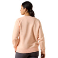 Woman wearing a peach-colored sweatshirt on a white background