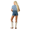 Woman wearing a blue t-shirt, denim shorts, and white cowboy boots on a white background