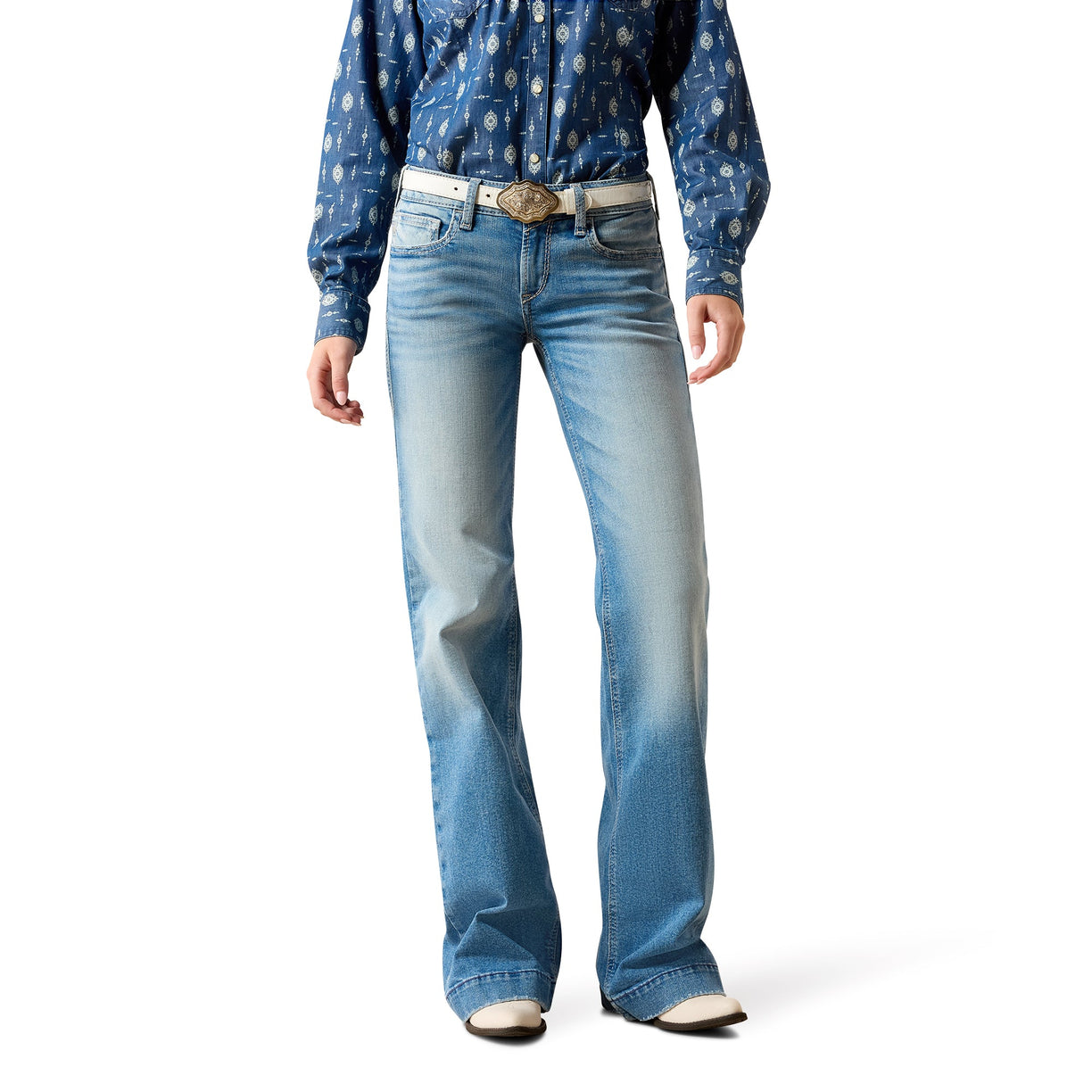 Person wearing blue jeans and a patterned shirt on a white background