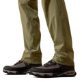 Close-up of beige pants and black hiking shoes on a white background