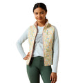Woman wearing a floral patterned vest over a white shirt and green pants on a white background