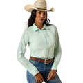 A woman modeling a light mint green long-sleeve western shirt with embroidered details on the sleeves, paired with a straw cowboy hat, brown belt, and blue jeans against a white background.