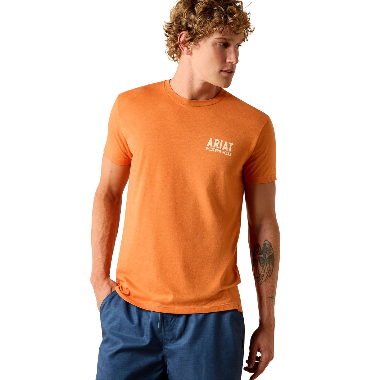 Man wearing an orange Ariat t-shirt on a white background