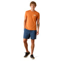 Man wearing an orange t-shirt and blue shorts on a white background