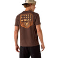 Man wearing a brown Ariat t-shirt with a logo on the back against a white background