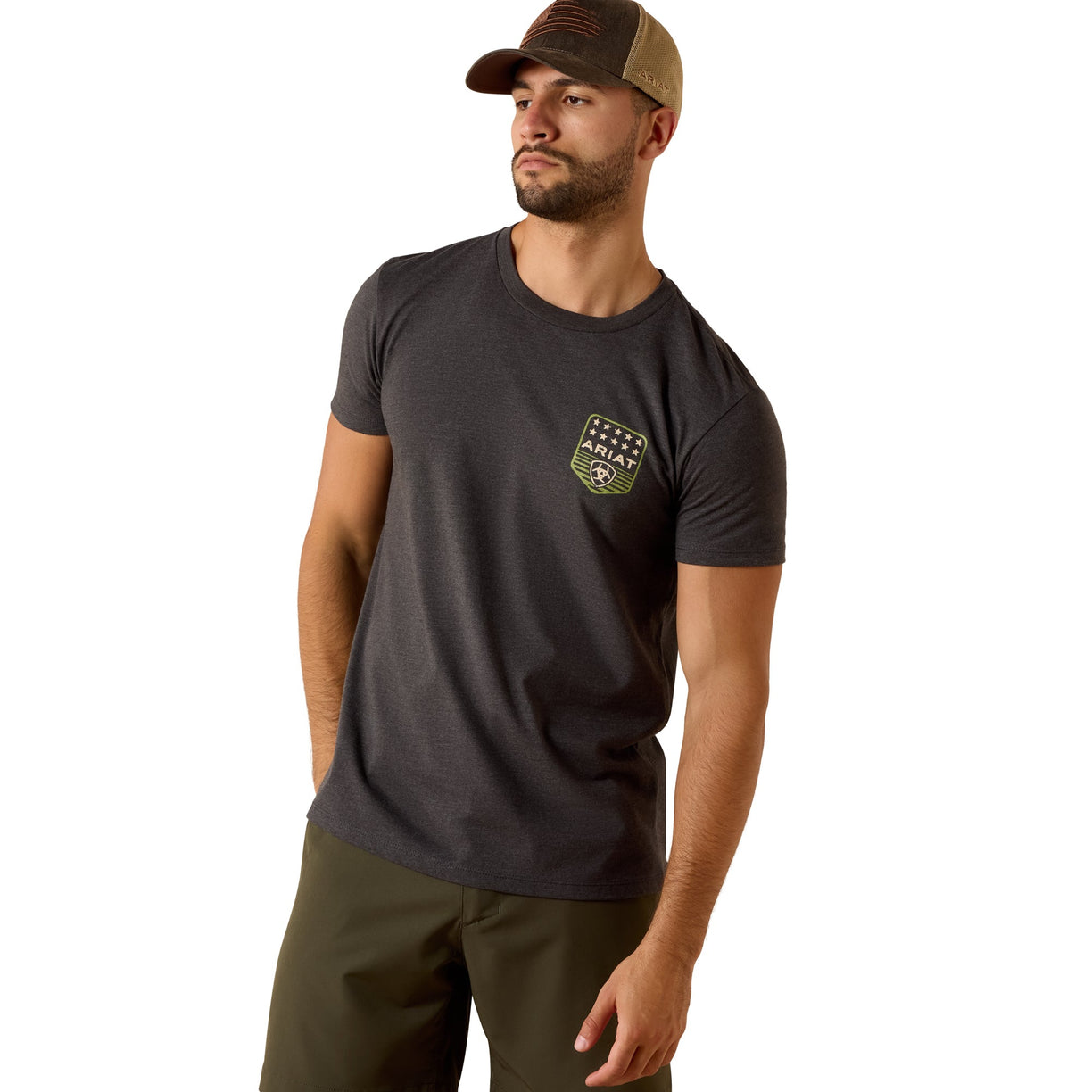 Man wearing a dark gray t-shirt with a logo and green pants on a white background