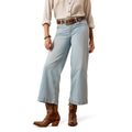 Model wearing light blue crop Ariat jeans and brown cowboy boots.