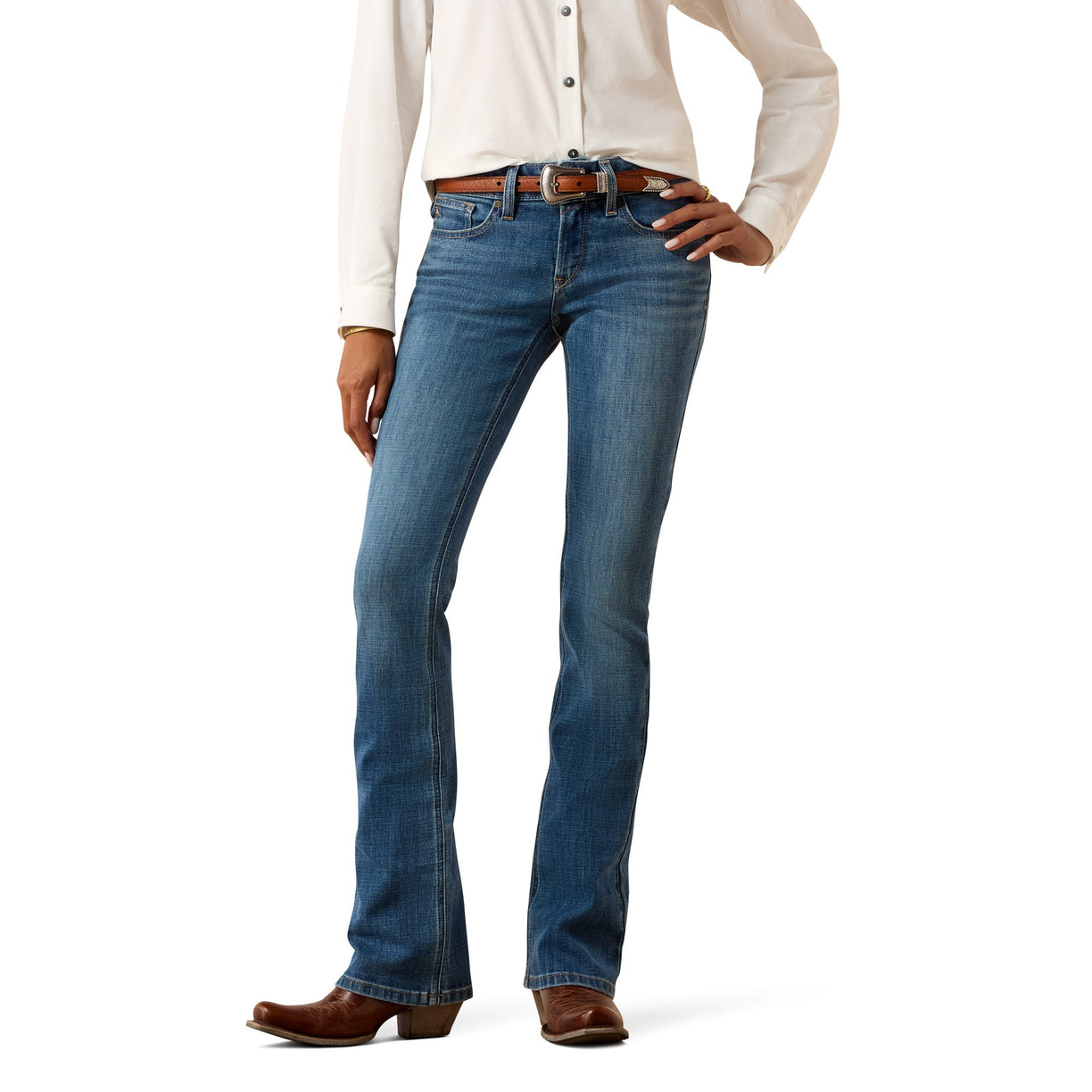A model wearing a pair of blue western-style boot cut jeans with a brown leather belt, paired with a cream button-down shirt and brown cowboy boots, shown from the waist down on a white background.