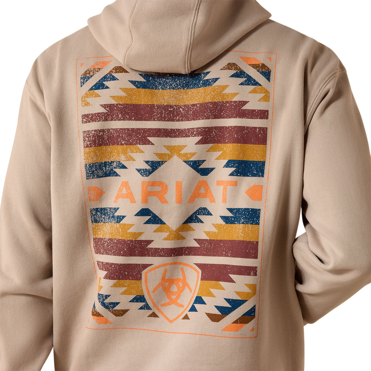 A beige hoodie shown from the back, featuring a large distressed geometric print with orange, blue, and brown stripes and the word ARIAT across the center.