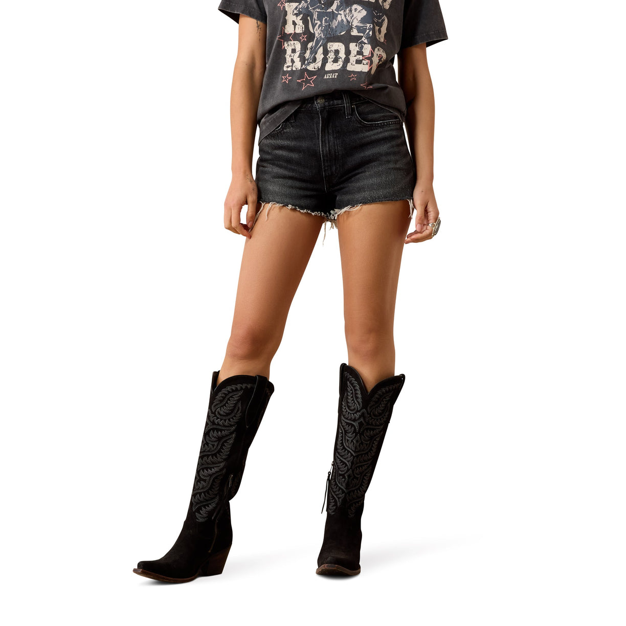 Model wearing black knee-high boots, black Ariat denim shorts, and a graphic t-shirt on a white background
