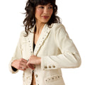 Woman wearing a white blazer with decorative buttons on a white background
