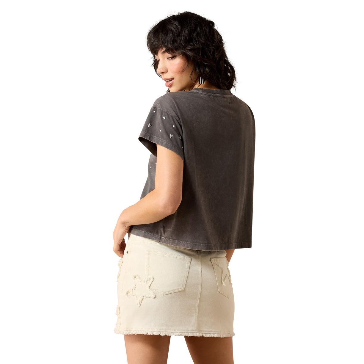Woman wearing a dark gray t-shirt and beige skirt on a white background