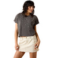 Woman wearing a dark gray t-shirt with star patterns and a white skirt on a white background