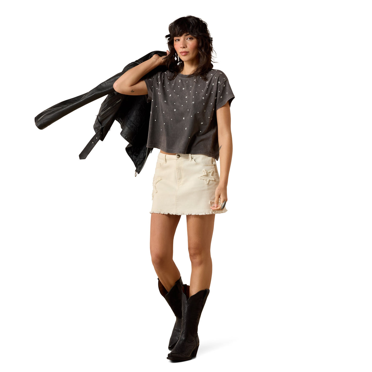 Woman wearing a dark gray t-shirt with star patterns, white shorts, and black boots on a white background