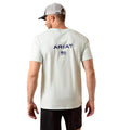 Man wearing a white Ariat t-shirt with a logo on the back against a beige background