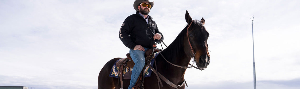 Cowboy wearing Ariat denim riding a horse in the snow