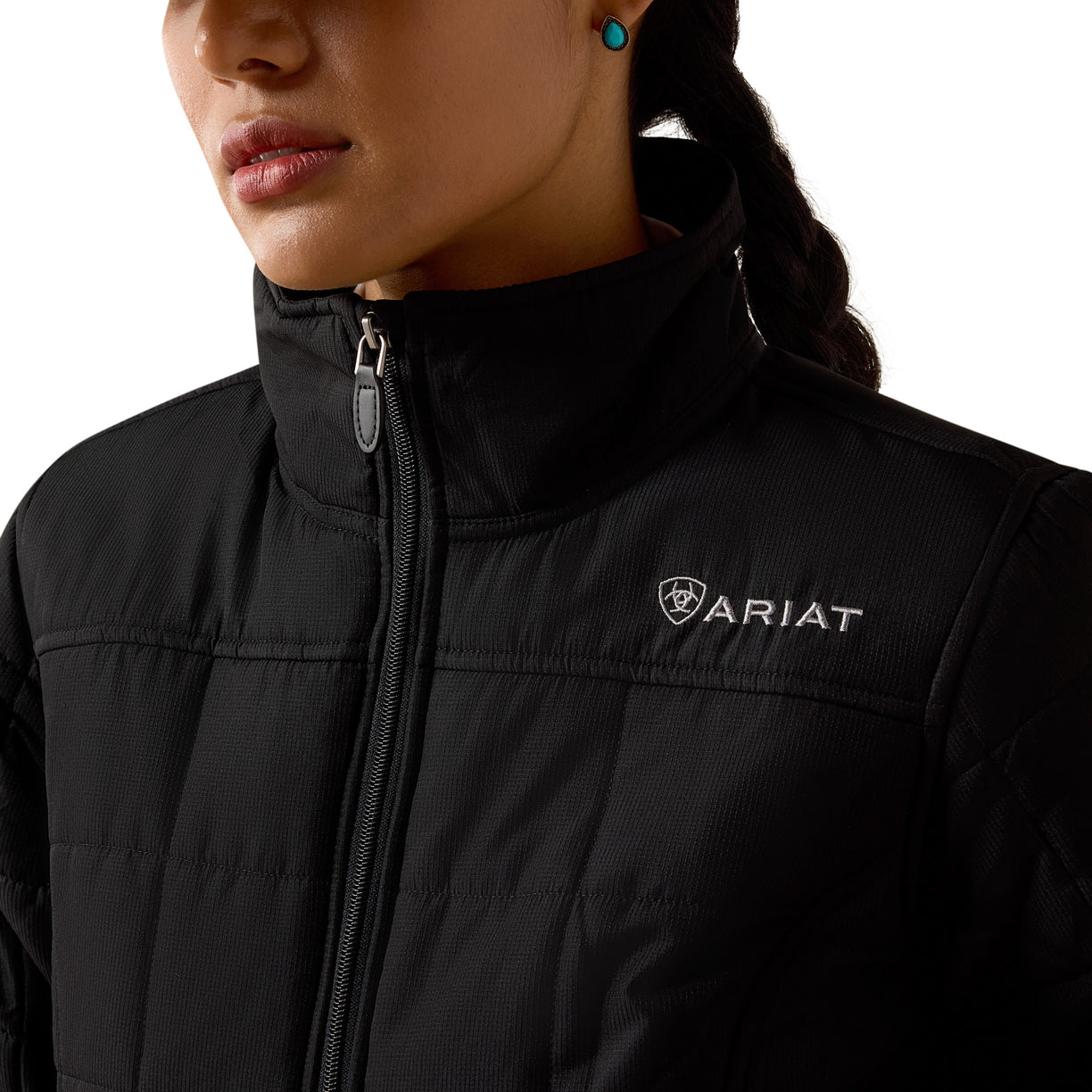 Close-up of a person wearing a black Ariat jacket with a white logo.