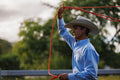 Man in a cowboy hat holding a red lasso with a blurred green background