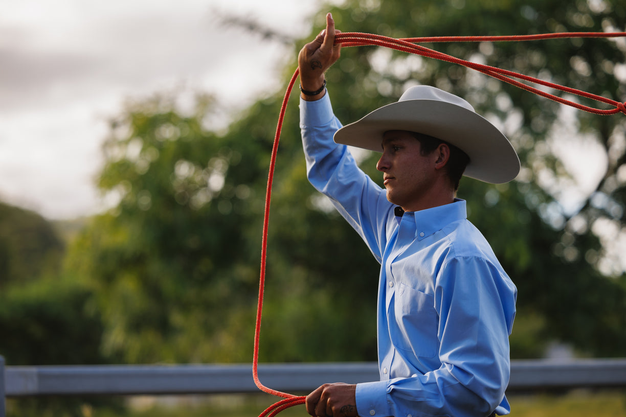 Man in a cowboy hat holding a red lasso with a blurred green background