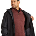 Man wearing a black jacket over a maroon shirt on a white background