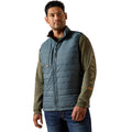 Man wearing a blue and green quilted vest with Carhartt logo on a white background