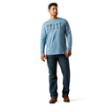 Man wearing a light blue long-sleeve shirt with 'Ariat' branding on a white background