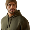 Man wearing a green hoodie and beanie on a white background