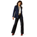 Woman wearing a blue blazer and dark jeans on a white background