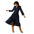 Woman wearing a navy blue dress with long sleeves and a belt, standing on a white background.