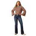 Woman wearing a brown sweater and blue jeans on a white background
