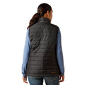 Person wearing a black puffer vest over a blue shirt on a white background
