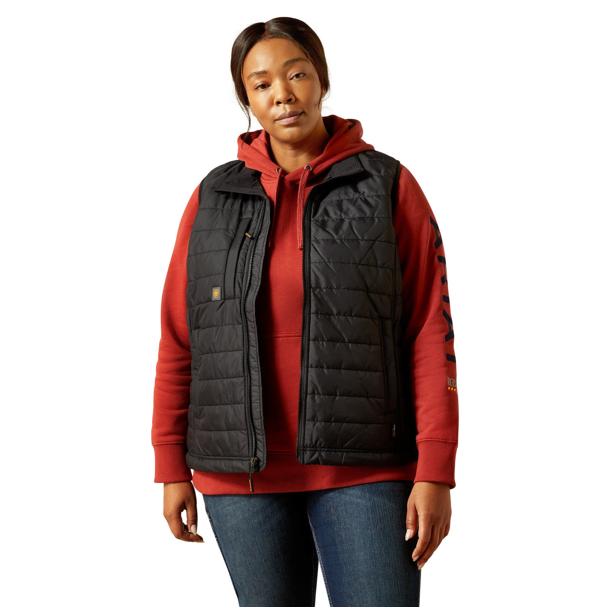 Person wearing a red hoodie with a black quilted vest on a white background
