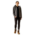 Person wearing a gray jacket with a hood, black pants, and brown boots on a white background