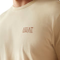 Man wearing a beige t-shirt with 'Ariat Supply' logo on the back, standing against a white background.