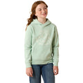 A young girl with red hair tied back, wearing a light sage green pullover hoodie with a white horseshoe graphic and blue jeans, standing against a plain white background.