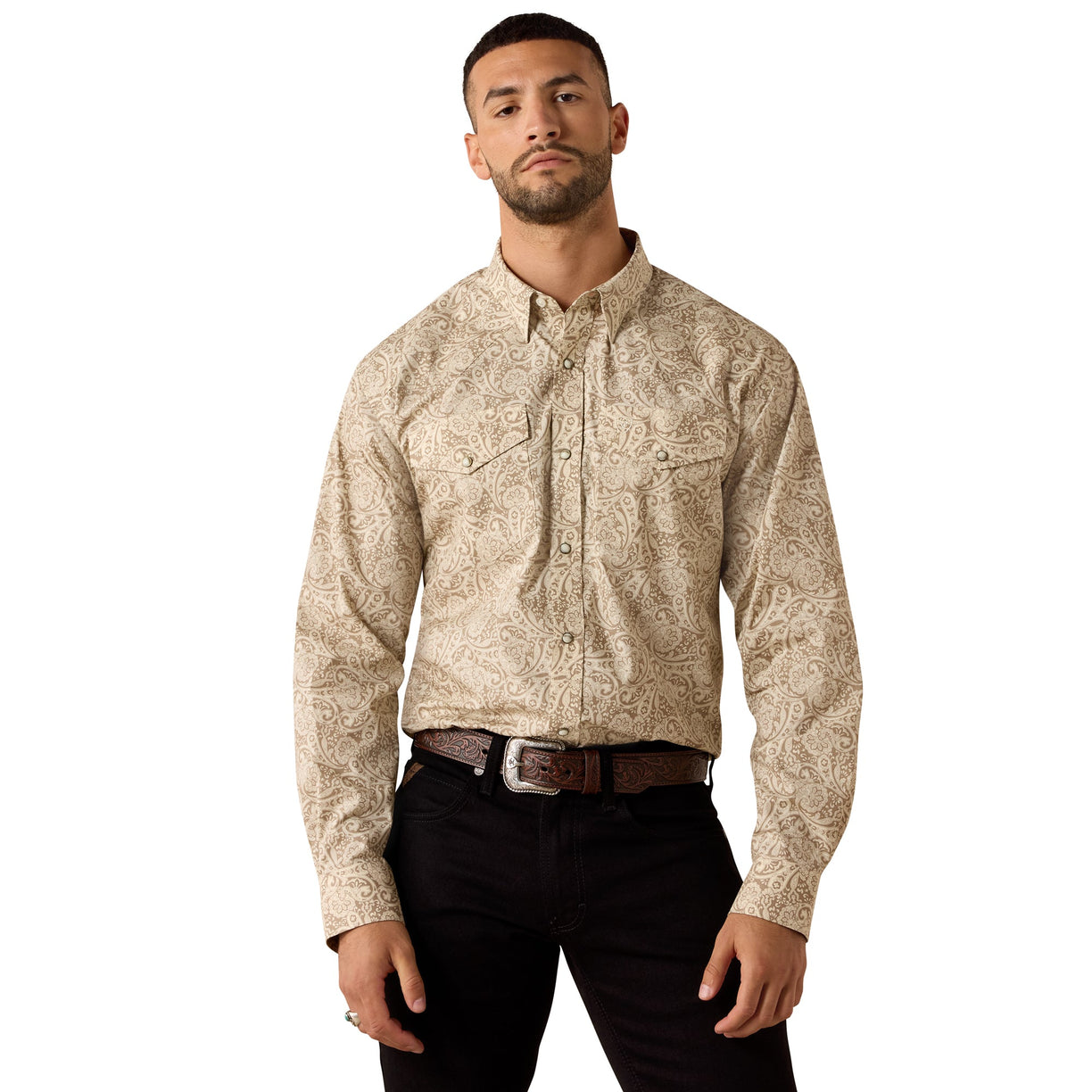 A man wearing a beige and brown paisley patterned long-sleeve western shirt with black pants, standing against a plain white background.